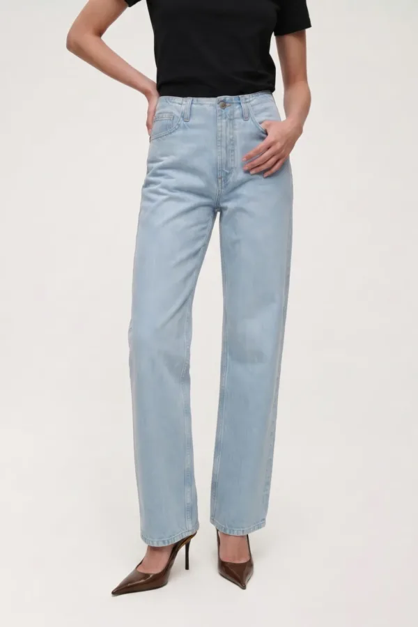 Full-length shot of a person wearing light-wash high-waisted jeans, a black top, and brown pointed-toe heels, with hands on hips.
